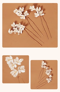Detailaufnahme von drei Braut-Haarnadeln mit weißen Keramikblumen und goldenen U-förmigen Pins