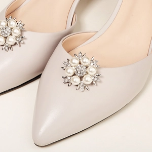 Detail von Perlen- und Strass-Blumenschnalle auf eleganten spitzen Brautschuhen