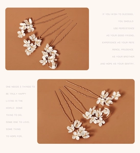 Detail von weißen Blumenhaarnadeln mit Goldakzenten und U-förmigen Metall-Haarspangen