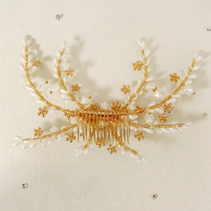 Handmade bridal hair comb with pearls and golden flowers on a cream textured background