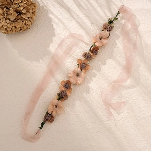 Détail d'un bandeau floral artisanal avec rubans en mousseline rose et roses en soie