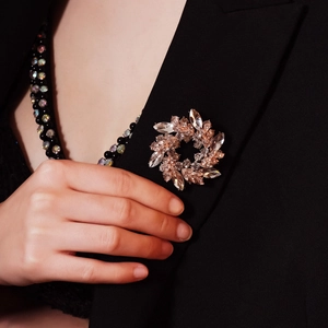 Eleganter roségoldener Blumenkranz-Brosche mit funkelnden Kristallen auf schwarzem Jackett