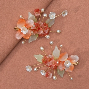 Détail de fleurs en résine faites main et perles blanches sur pinces à cheveux dorées