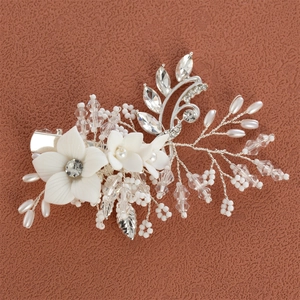 Close-up of handmade white resin flowers and pearls on a silver bridal hair clip