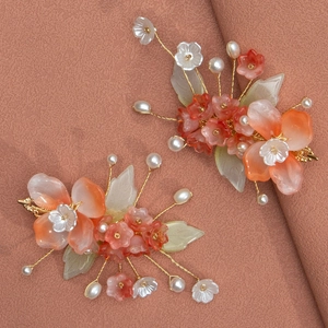 Détail de barrettes à fleurs en résine avec perles et fil doré pour coiffure mariée