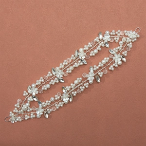Elegant bridal headband with white pearls, resin flowers, and crystals on a pink background