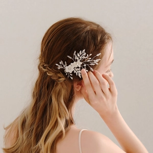 Elegant bridal hair clip with white clay flowers and silver rhinestones on model's hair