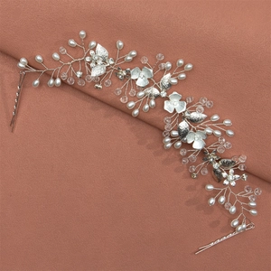 Close-up of handmade bridal hair vine with silver metal flowers and white pearls