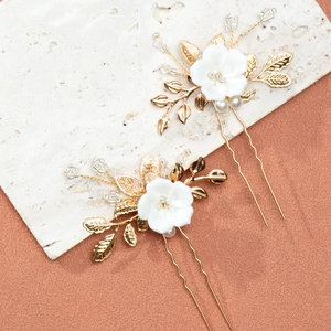 Detailansicht von U-förmigen Haarnadeln mit Keramikblumen, Goldblättern und Perlen
