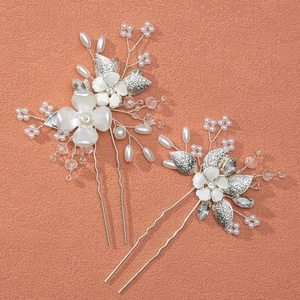 Detailed view of silver bridal hair pins with white flowers, pearls, and crystal beads