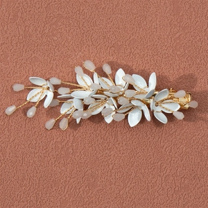 Detail of handmade bridal hair clip with white ceramic leaves and crystal beads