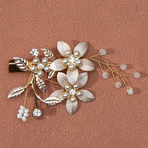 Macro detail of golden flower hair clip with pearls and rhinestones on pink background