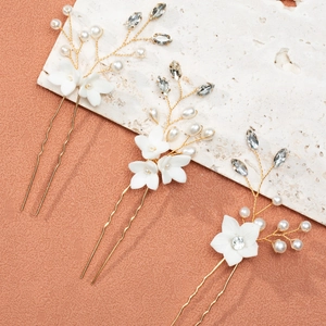 Detail of three bridal hair pins with white ceramic flowers, pearls and marquise rhinestones