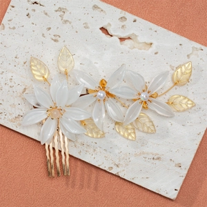 Detail of bridal hair comb with white acrylic flowers, pearls and golden leaves