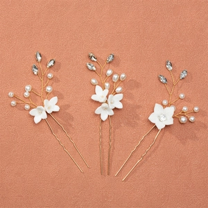 Detail of bridal hair pins set with handmade ceramic flowers and pearls on rose background