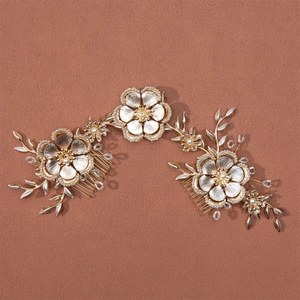 Macro shot of bridal hair comb with metal flowers, white pearls and crystal branch details