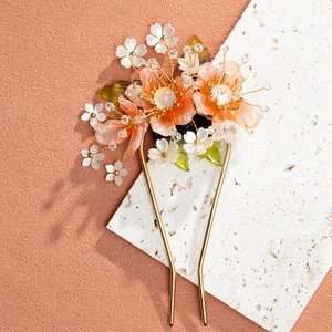 Close-up of golden Chinese hairpin with orange resin petals and green leaves detail