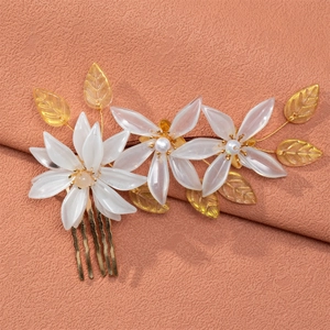 Macro shot of bridal hair comb with creamy acrylic flowers and pearls on pink fabric