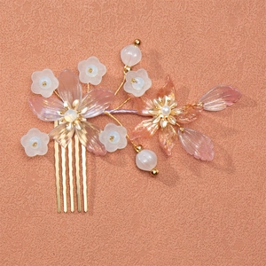 Detailed view of pink resin flower hair comb with golden metal branches and pearls