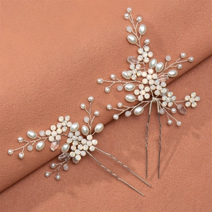 Handmade bridal hair pins set with white pearls and rhinestones on a brown fabric background