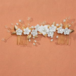 Handmade bridal hair comb with ceramic flowers and pearls on a warm peach background