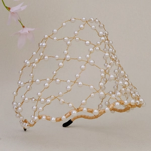 Elegant handmade pearl bridal headband with gold wire mesh and floral decor background