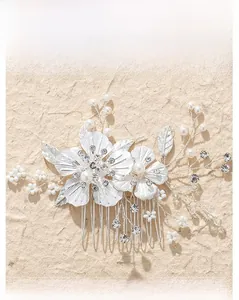 Détail d'un peigne à cheveux de mariée argenté avec fleurs métalliques et perles blanches