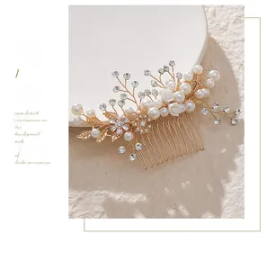 Close-up of golden bridal hair comb with white pearls, crystals and floral branch details