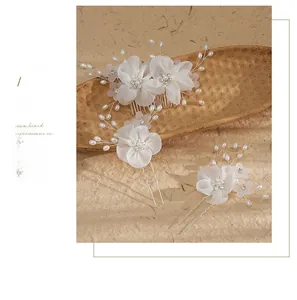 Detail of handmade bridal hair comb and pins with white fabric flowers and pearls
