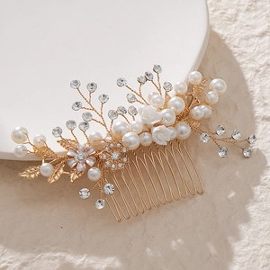 Elegant bridal hair comb with pearls, rhinestones and golden leaves on white ceramic tray