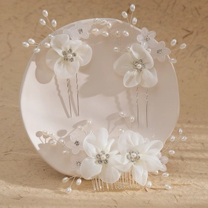 Elegant bridal hair set with white fabric flowers, pearls, and crystals on a white plate