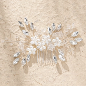 Silver bridal hair comb with pearls and rhinestones on textured beige paper