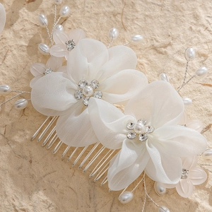 Handmade bridal hair comb with white mesh flowers, pearls, and rhinestones on beige paper