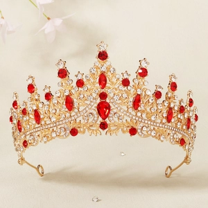Detail of a luxury bridal crown with golden filigree, red gems, and sparkling crystals