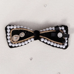 Detail of velvet black bow hair clip with white pearls and sparkling crystal accents