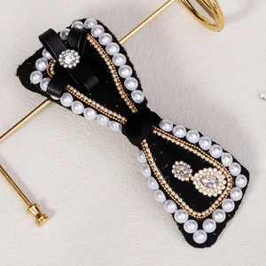 Detail showing elegant black velvet bow hair clip with pearls and sparkling rhinestones