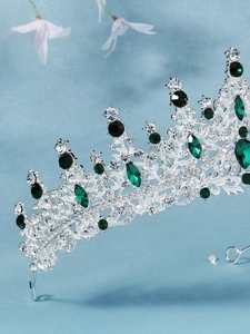 Close-up of silver bridal crown with emerald green stones and intricate diamond crystals