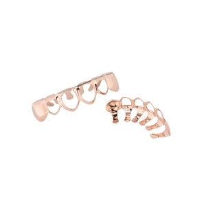 Gros plan d'un ensemble de grillz dentaires ajourés en forme de cœur couleur or rose