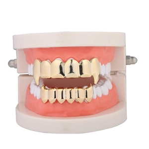 Polished gold vampire fangs grillz set on a dental model for hip hop fashion style