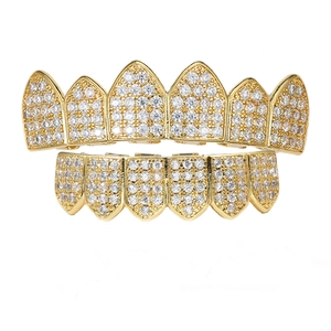 Detail view of hip hop gold grillz featuring micro-paved cubic zirconia on white surface