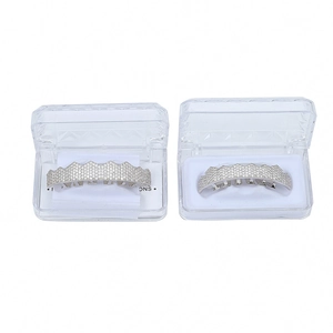 Detailed view of silver grillz set with sparkling zircons and a transparent storage box