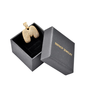 Detalle del colgante M de hip-hop con pavé de circonitas y caja de regalo de joyería negra