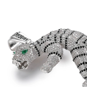 Macro detail of 3D tiger pendant featuring white and black crystals with green emerald eyes