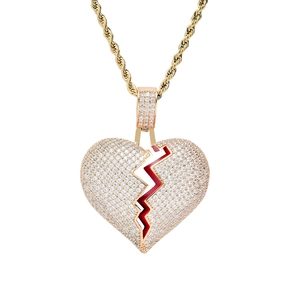 Détail macro du pendentif cœur brisé glacé avec accents rouges et chaîne dorée