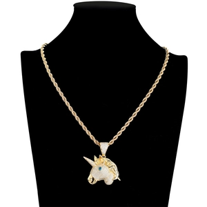 Macro shot of gold hip hop unicorn pendant featuring pave zircon and blue agate eyes