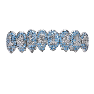 Makro-Detail von silbernem Hip-Hop-Zahnschmuck mit 414er Muster und blauen Zirkonen