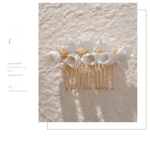 Détail d'un peigne à cheveux de mariée fait main avec fleurs blanches et perles dorées
