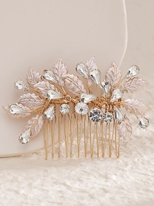 Macro detail of bridal hair comb with pink leaves and sparkling crystals on gold wire