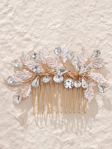 Detailed close-up of golden bridal hair comb with white enamel leaves and clear crystals