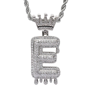 Close-up of iced out crown letter E pendant with liquid drip effect on rope chain